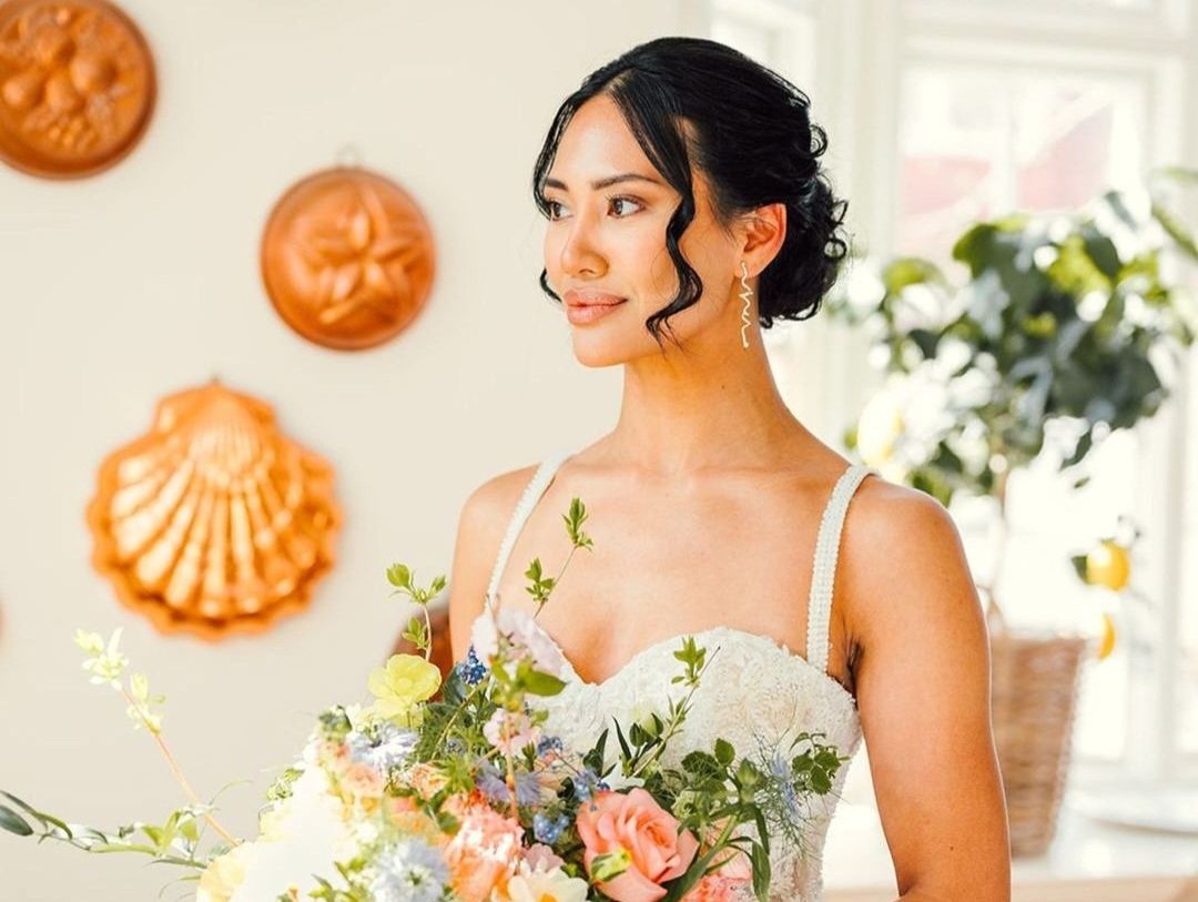 Brud i vit klänning håller en färgglad blomsterbukett.
