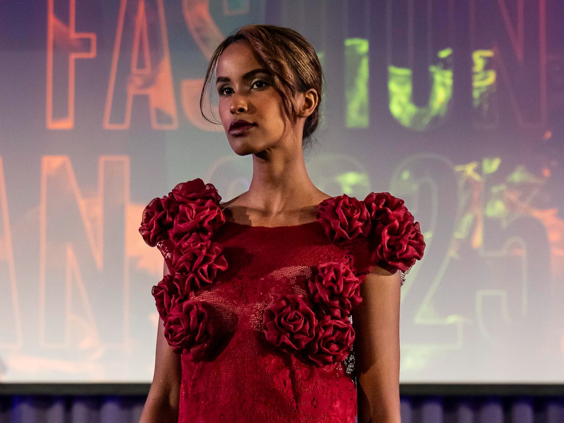 Modell i röd klänning på catwalk.